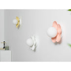 Three of these Clérachic wall lights are mounted together, in yellow, white and pink, the pink one closest and lit.