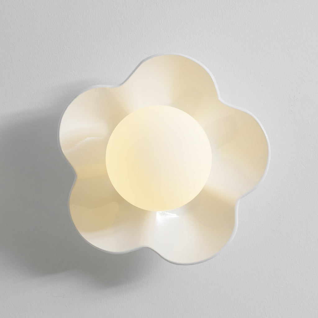 Its ball lit, this Clérachic wall light in a pale cream finish sits against a plain grey backdrop.