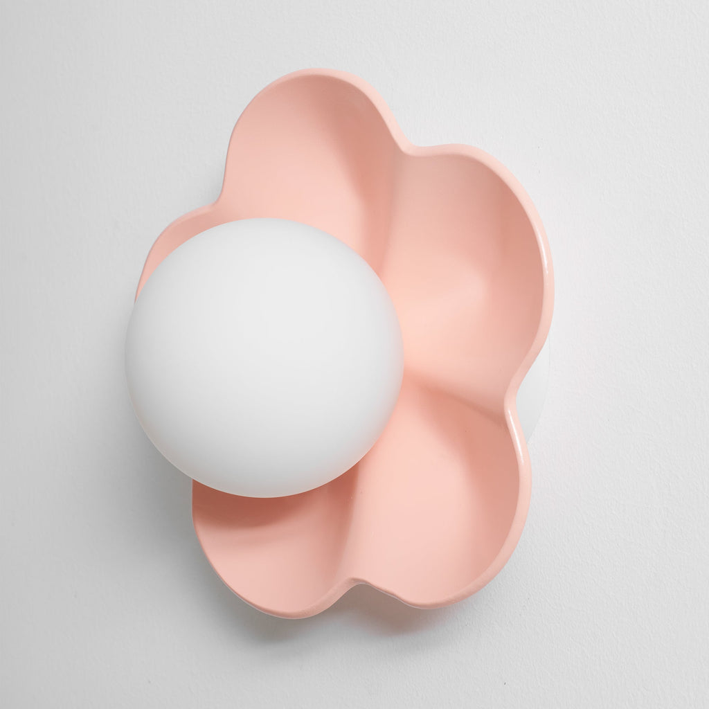 With a soft shadow to one side, this Clérachic wall light in pink sits unlit against a plain backdrop.