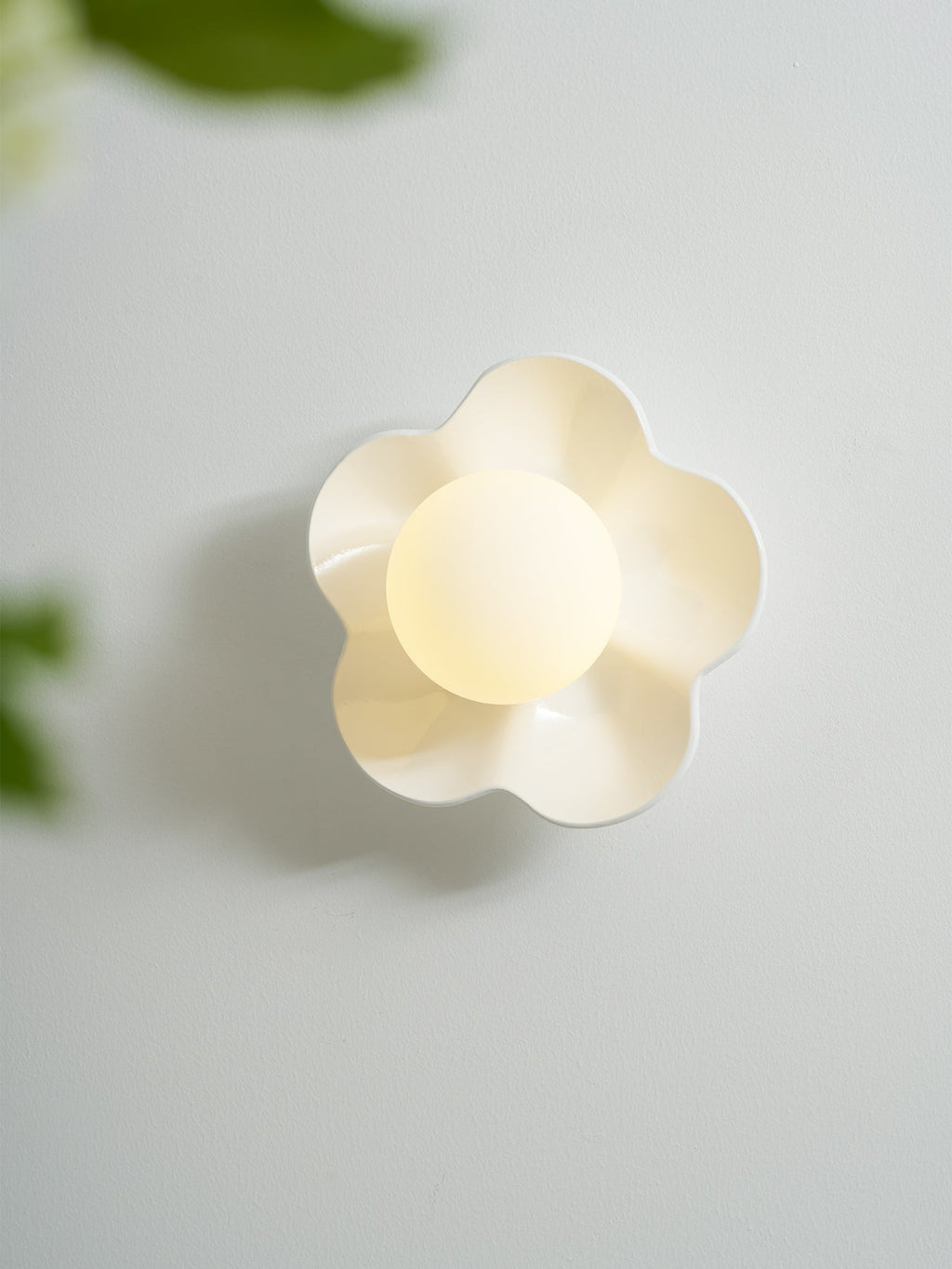 With a blurred leaf crossing the foreground, this Clérachic wall light in white glows on the wall.