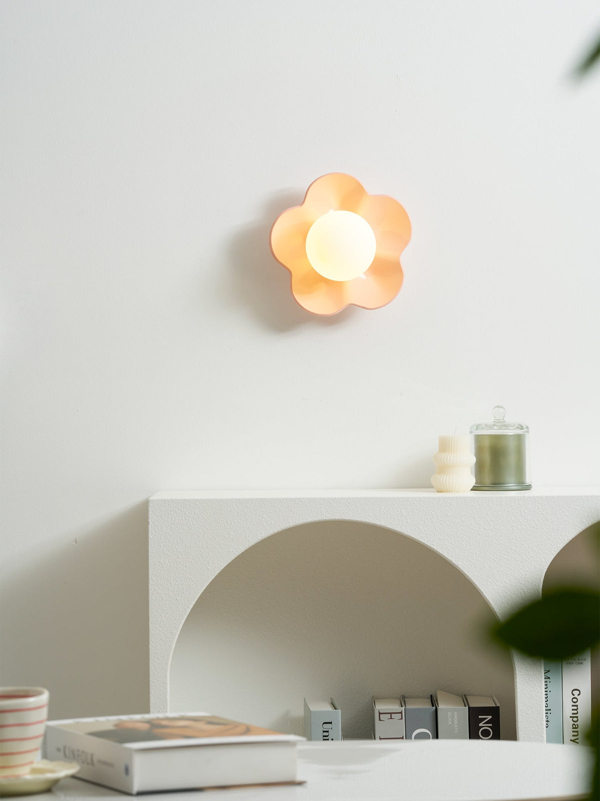 Mounted unlit above the same console table, this Clérachic wall light in pink sits beside a small candle below.