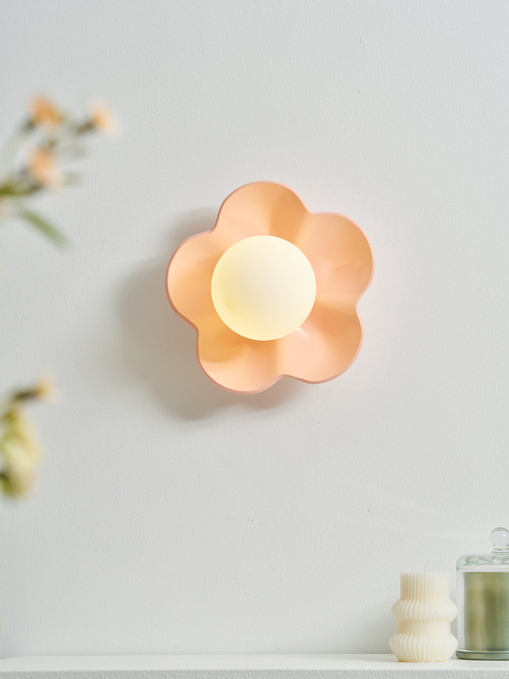 With flowers and a candle blurred in the foreground, this Clérachic wall light in pink glows on the wall.