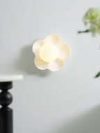 With greenery blurred in the foreground, this Clérachic wall light in white glows on the wall.