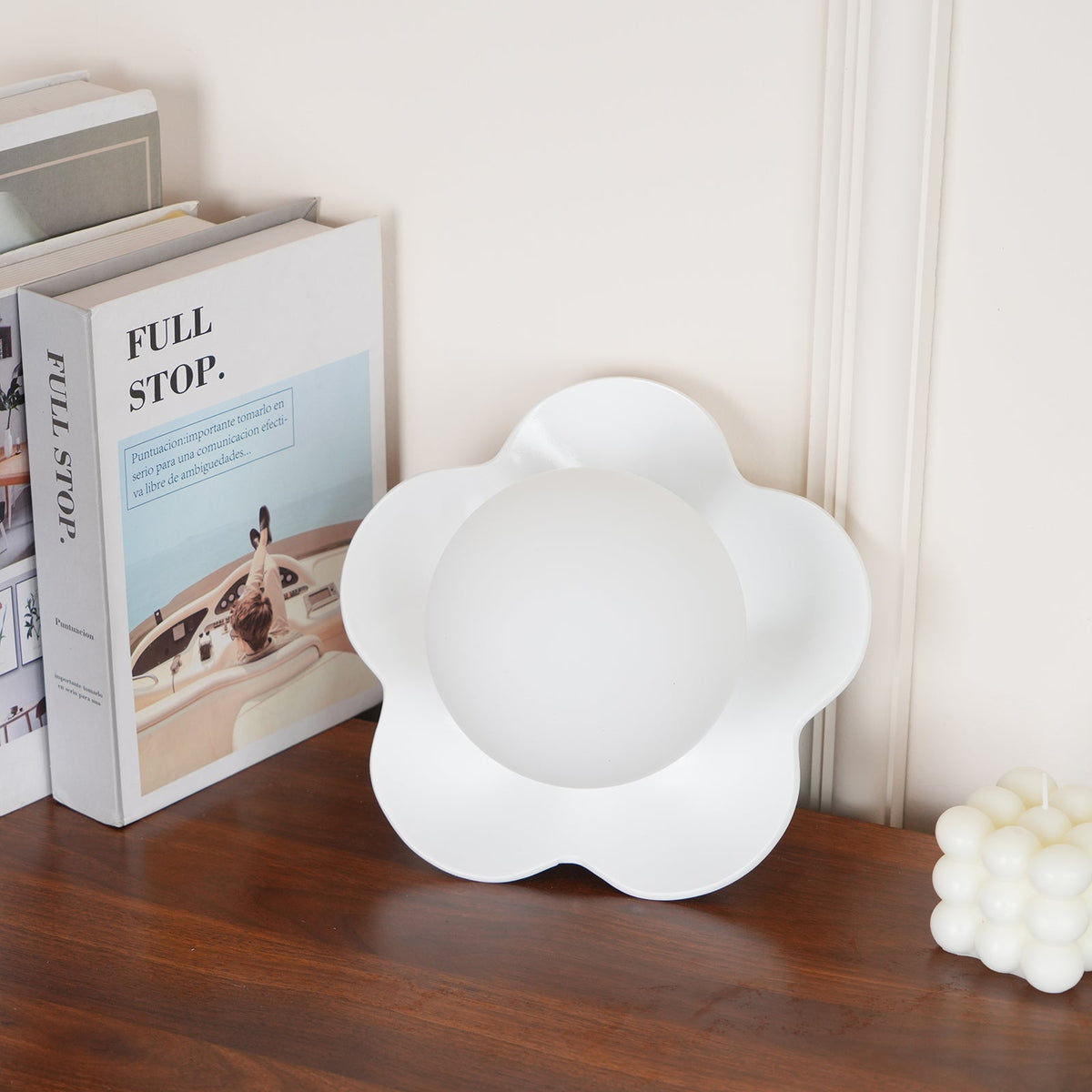 A second view of this Clérachic wall light in white beside the same books and candle.