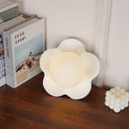 Its ball lit, this Clérachic wall light in white stands beside a stack of books and a candle.