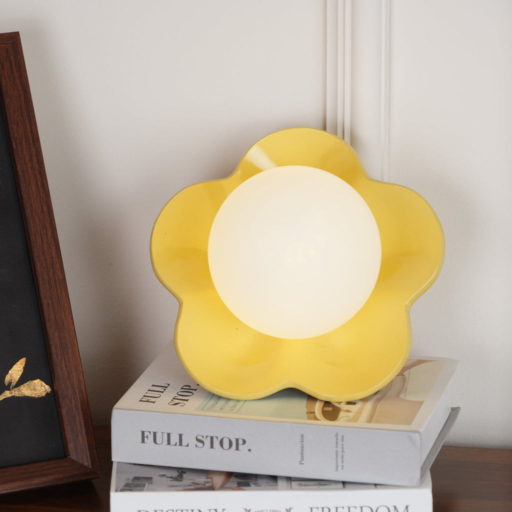 Beside a black-framed print, this Clérachic wall light in yellow stands unlit on a stack of books.