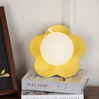 Beside a black-framed print, this Clérachic wall light in yellow stands unlit on a stack of books.