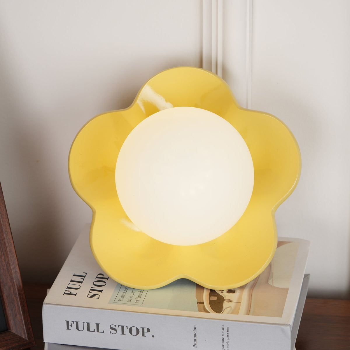 Its ball lit, this Clérachic wall light in yellow stands on a stack of books.