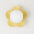 Close studio shot of this Clérachic wall light in yellow, its ball lit against a textured pale backdrop.