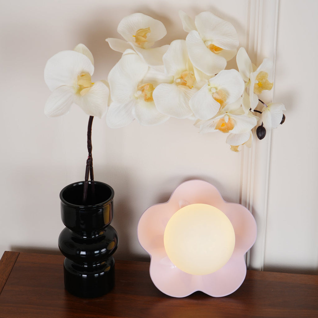 A third angle of this Clérachic wall light in pink, orchid blooms arching overhead on the table.