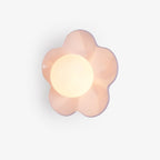 A close studio view of this Clérachic wall light in pink, its five petals framing the lit glass ball.
