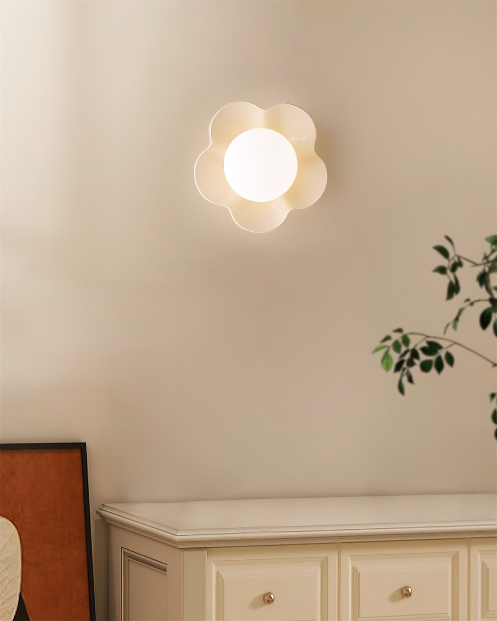 Above a pale cabinet with a plant nearby, this Clérachic wall light in white glows softly on the wall.