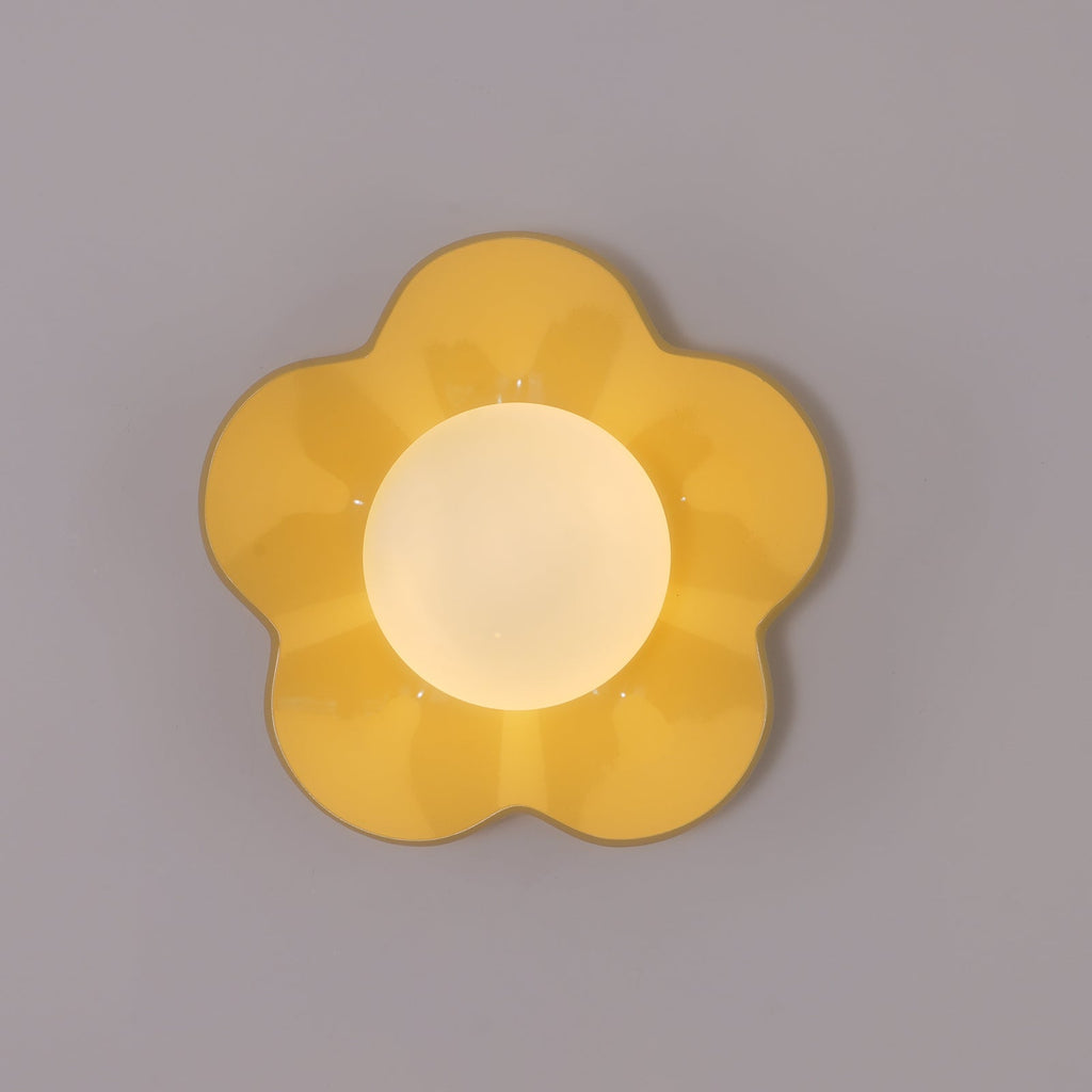 Close studio shot of this Clérachic wall light in yellow, its petals unlit against a plain grey backdrop.