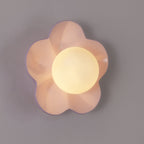 Close studio shot of this Clérachic wall light in pink, its glass ball glowing softly.