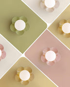 Four colour options of this Clérachic flower-shaped wall light shown on a diamond backdrop, including an olive-green and a tan version not sold here.