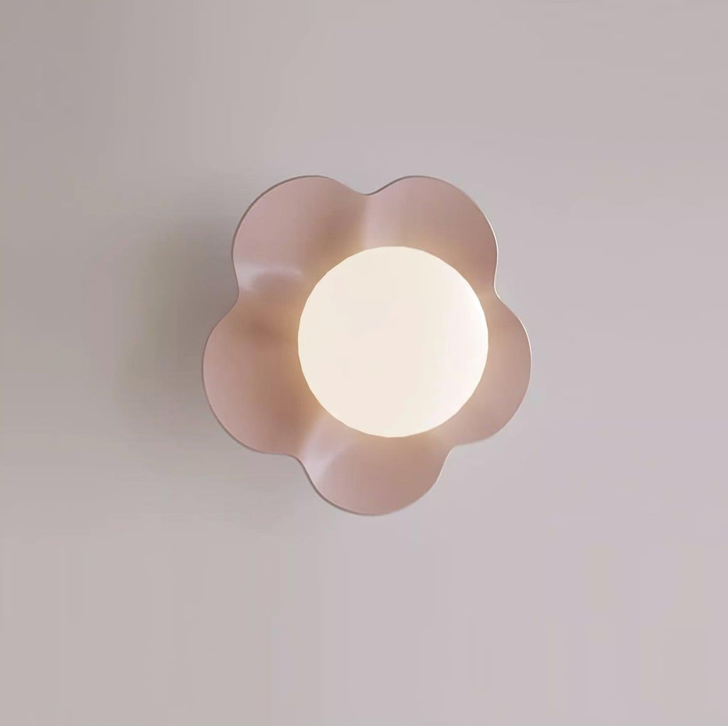 Close studio shot of this Clérachic wall light in a blush tone, its ball lit against a lavender backdrop.