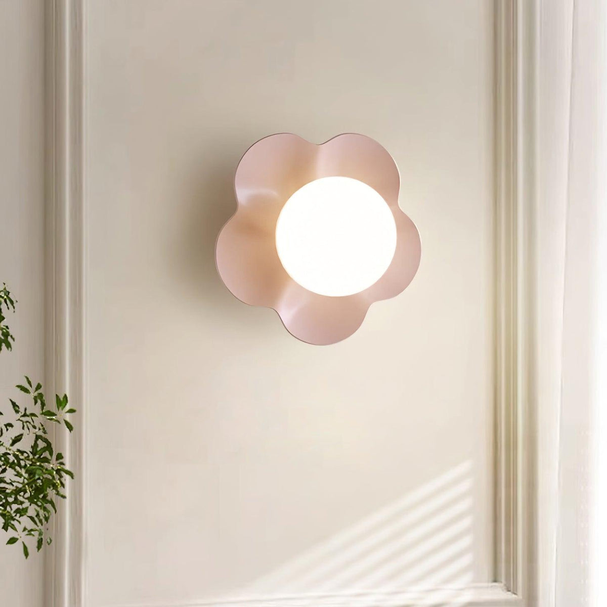 Mounted beside a sunlit window with a plant below, this Clérachic wall light in pink softens the corner.