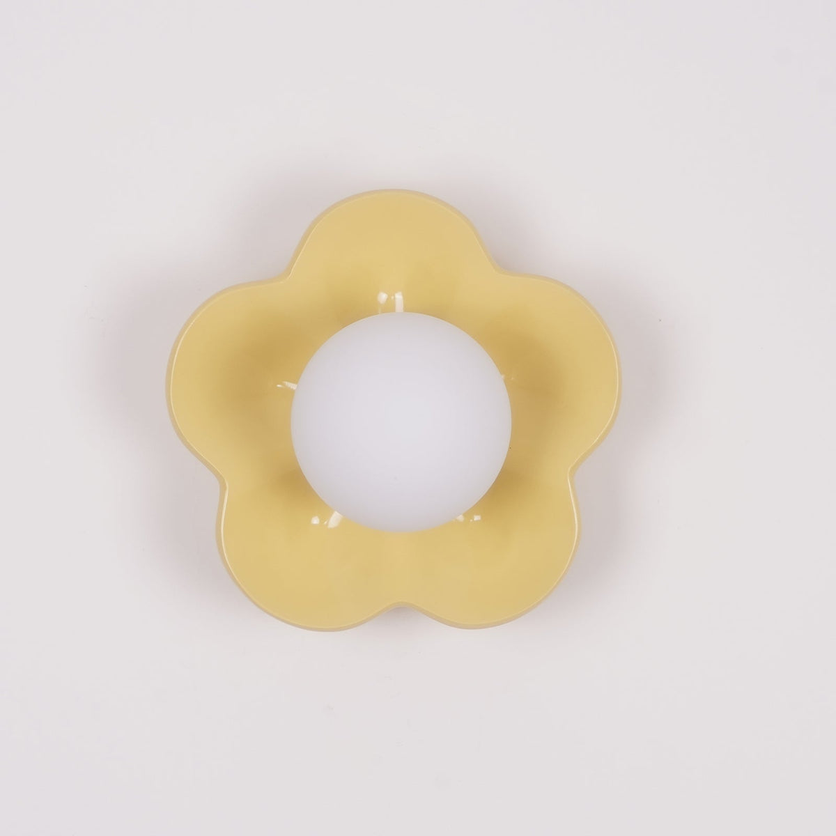 In a plain studio shot, this Clérachic wall light in a paler yellow sits unlit against a white backdrop.