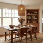 This Clérachic pendant hangs above a wood dining table with woven leather chairs, a wood hutch in the window-lit room behind.