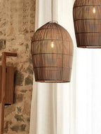 Against a stone wall and sheer curtain, this Clérachic pendant hangs near a wall sconce and a second pendant beyond.