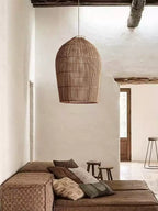Beneath rustic wood ceiling beams, this Clérachic pendant hangs above a low woven sofa with patterned cushions.