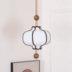 Fabric pendant light with gold frame against a neutral backdrop