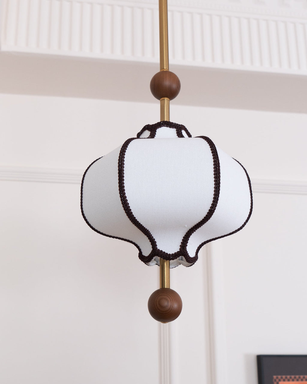 White fabric pendant light with gold frame and warm bulb