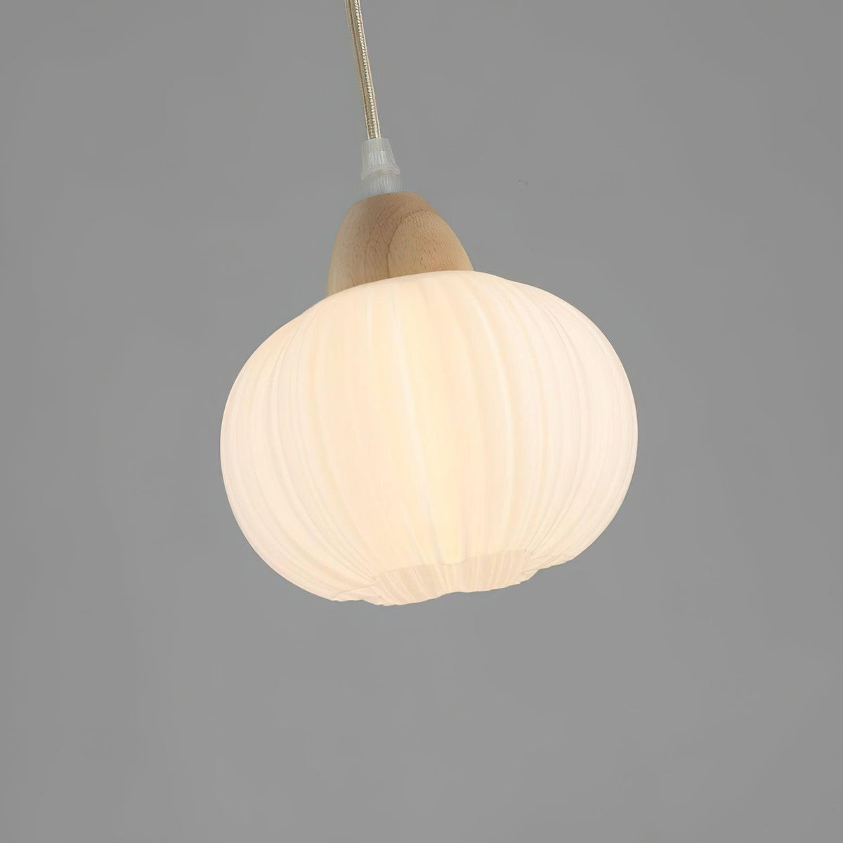 Clérachic fluted pendant lamp lit close up, warm light gathering in the pleated hem at the base of the shade.