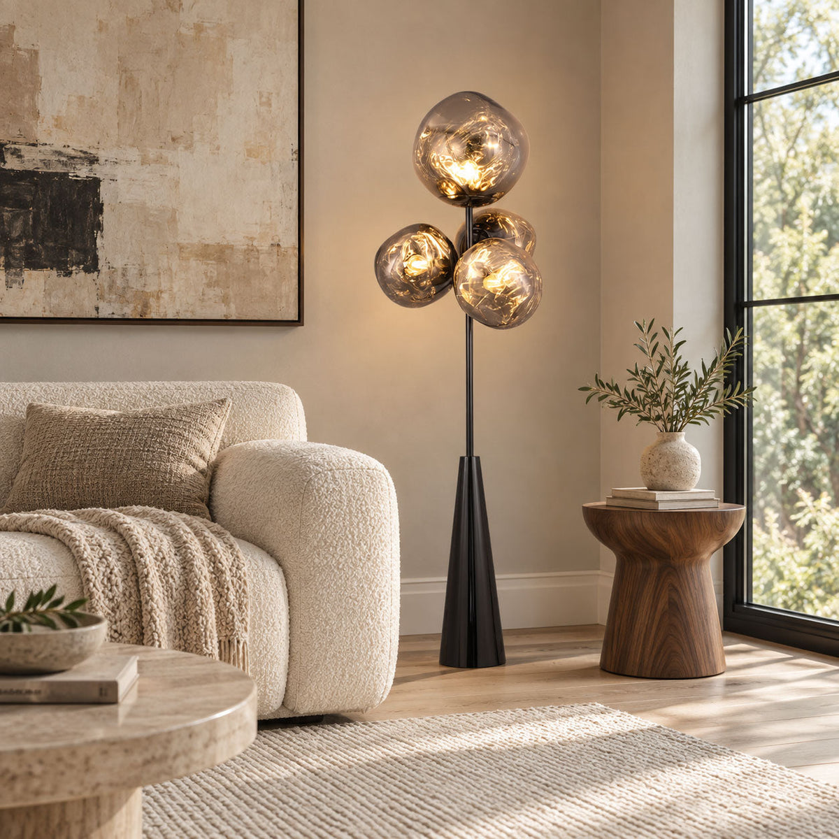 Clérachic floor lamp lit in a living room corner beside a cream boucle sofa, abstract art and tall windows framing the marbled glass globes.