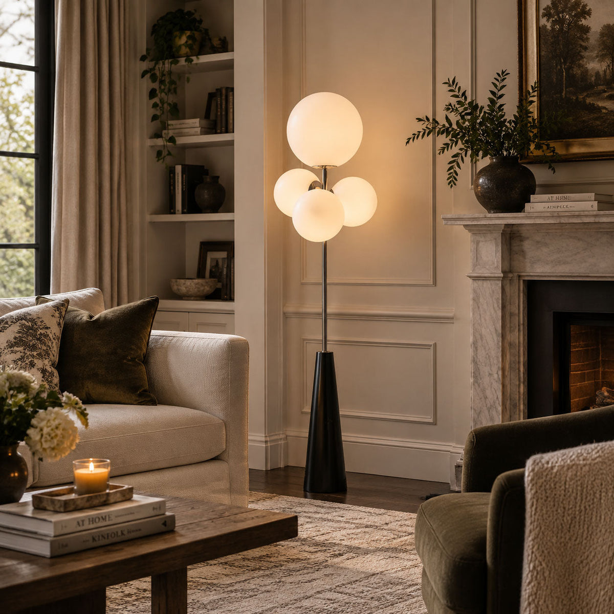 Clérachic floor lamp with frosted white glass globes lit beside a marble fireplace, its warm glow reaching a sofa and coffee table nearby.