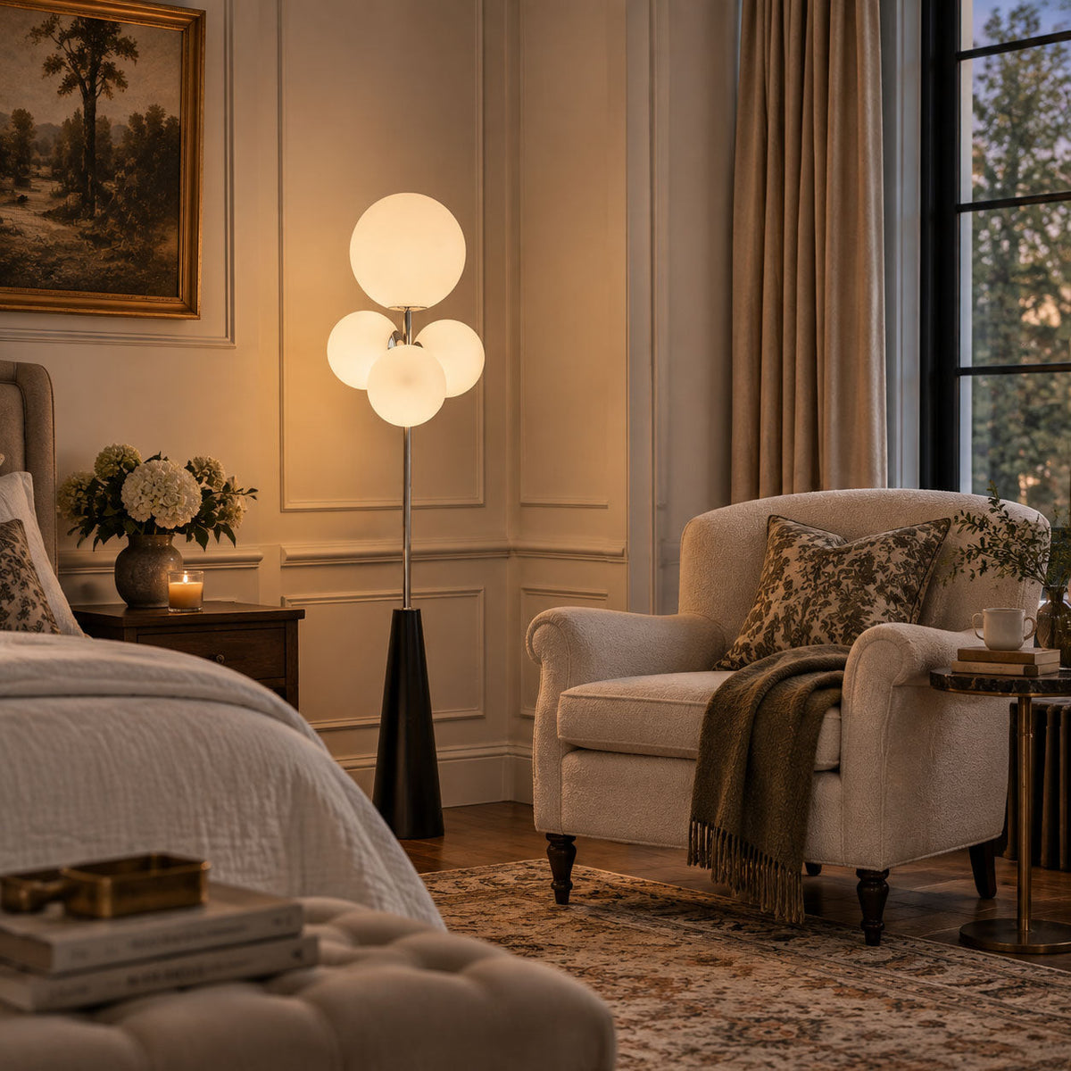 Frosted white glass globes glow beside a tufted armchair and floral painting, the black conical base grounding this Clérachic bedroom scene.