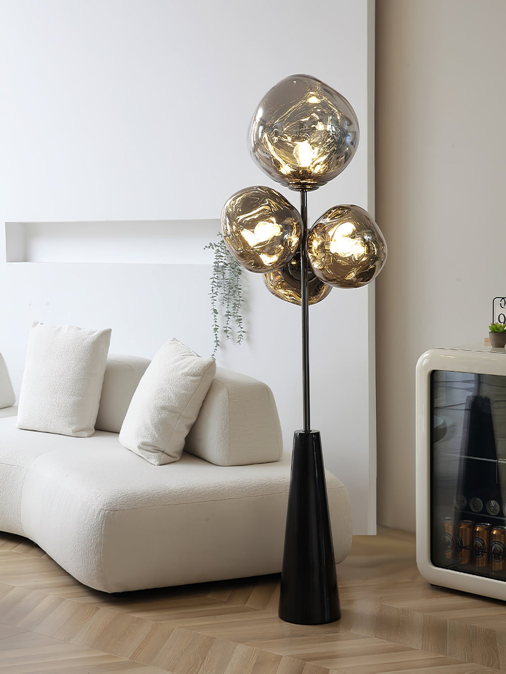 Clérachic floor lamp glowing in a pale, minimalist room, its smoke-glass globes rising beside a boucle sofa and a black bar cabinet.