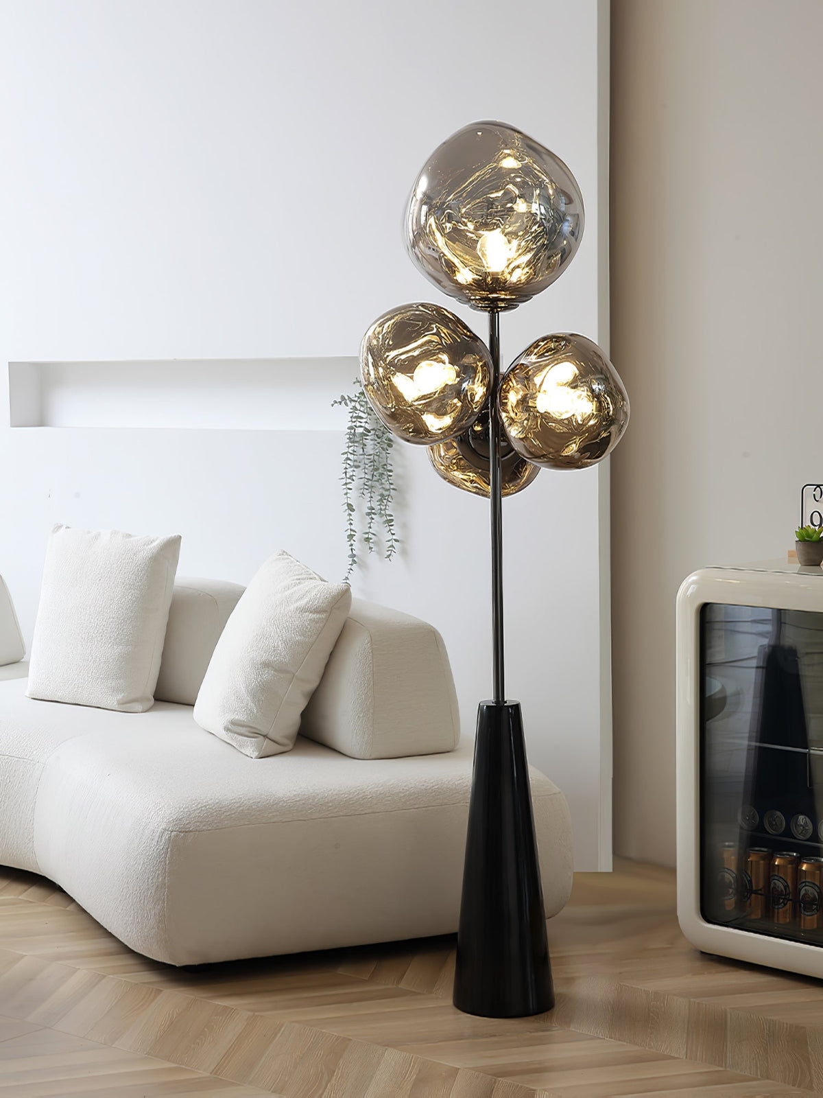 Clérachic floor lamp glowing in a pale, minimalist room, its smoke-glass globes rising beside a boucle sofa and a black bar cabinet.