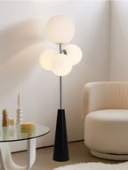 Clérachic floor lamp with frosted white globes lit beside a glass side table set with candlesticks, a faux-fur rug underfoot.
