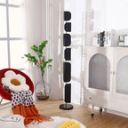 A stack of books and a tall vase with dried branches sit on the arched cabinet beside the lit Clérachic floor lamp and red chair.