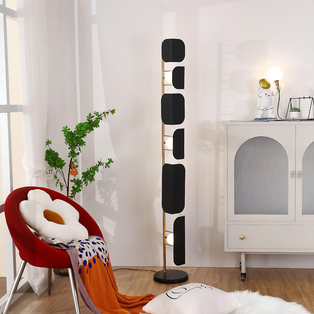 A tighter crop of the same corner, the Clérachic floor lamp's glass panels glowing beside the arched cabinet and potted plant.