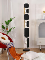 The Clérachic floor lamp lit beside the arched cabinet and red chair, an orange throw trailing onto the sheepskin rug below.