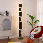A Clérachic black glass floor lamp glows in a living room corner beside a cream arched cabinet, a red flower-shaped chair and a sheepskin rug.