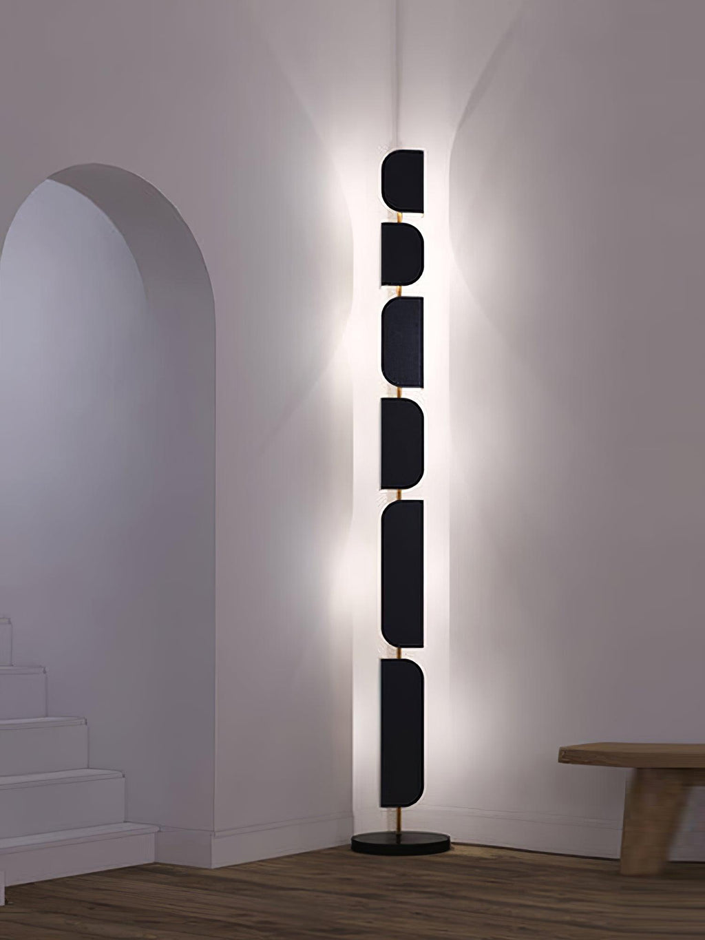 Near a stairwell archway, the Clérachic floor lamp casts a warm glow up the wall beside a low wood bench.