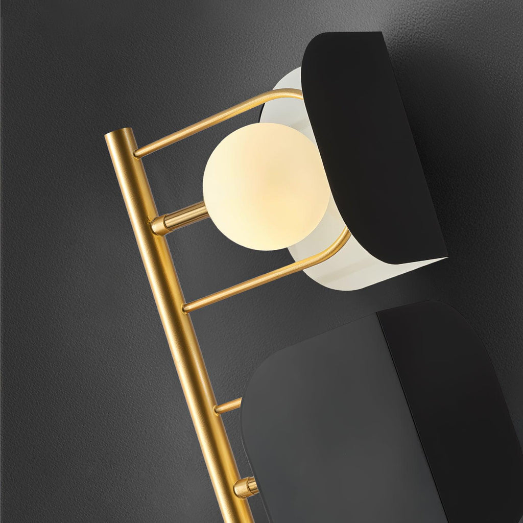 Close-up detail of the Clérachic floor lamp's gold ladder frame, showing one round opal glass globe lit beside a black glass panel.