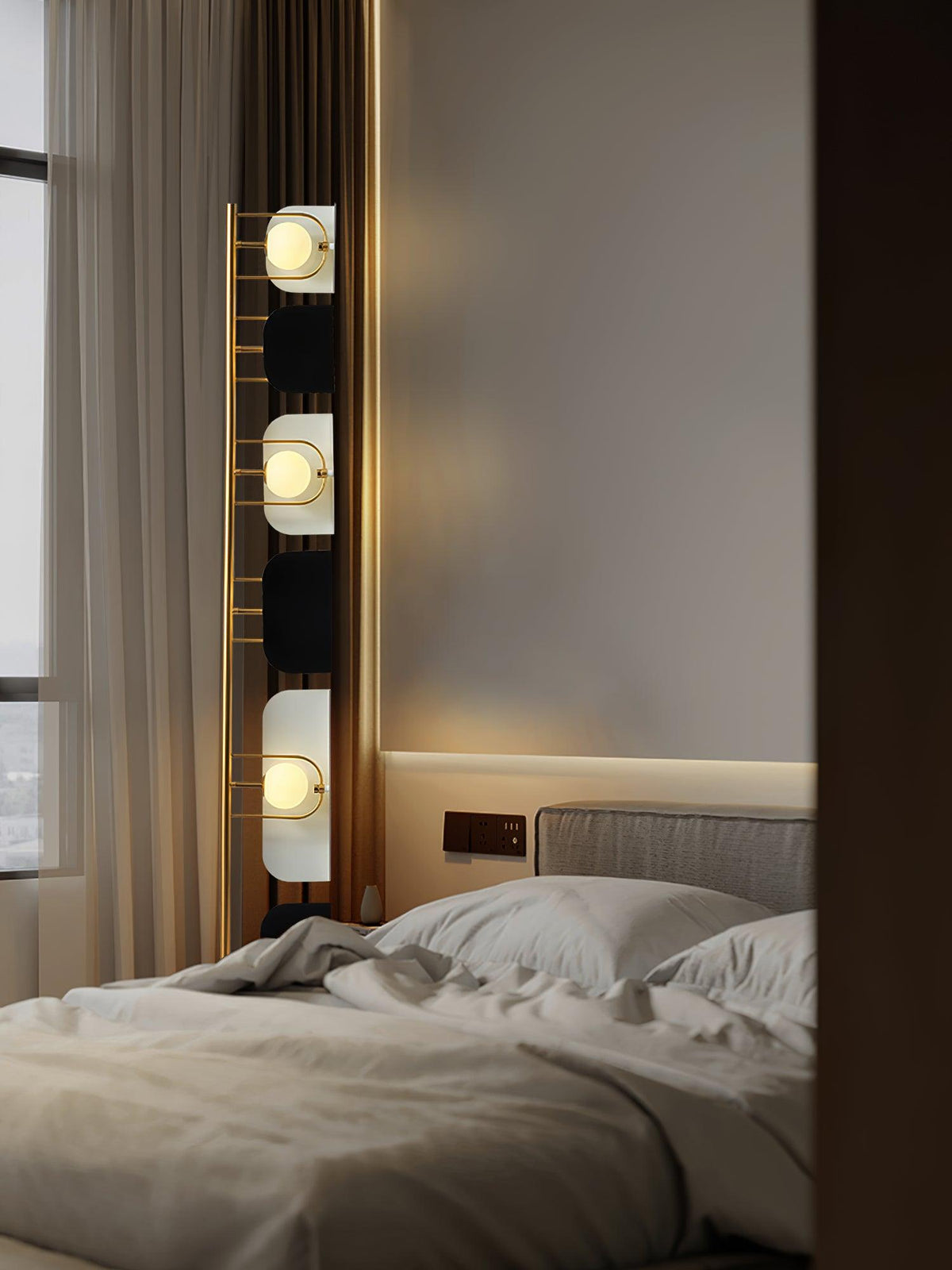 A close crop inside the bedroom shows the Clérachic floor lamp's top panels glowing above a made-up bed.