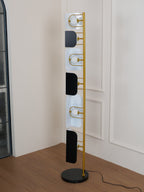 A vertical close crop shows the Clérachic floor lamp's gold rungs alternating with black glass panels and lit opal globes.