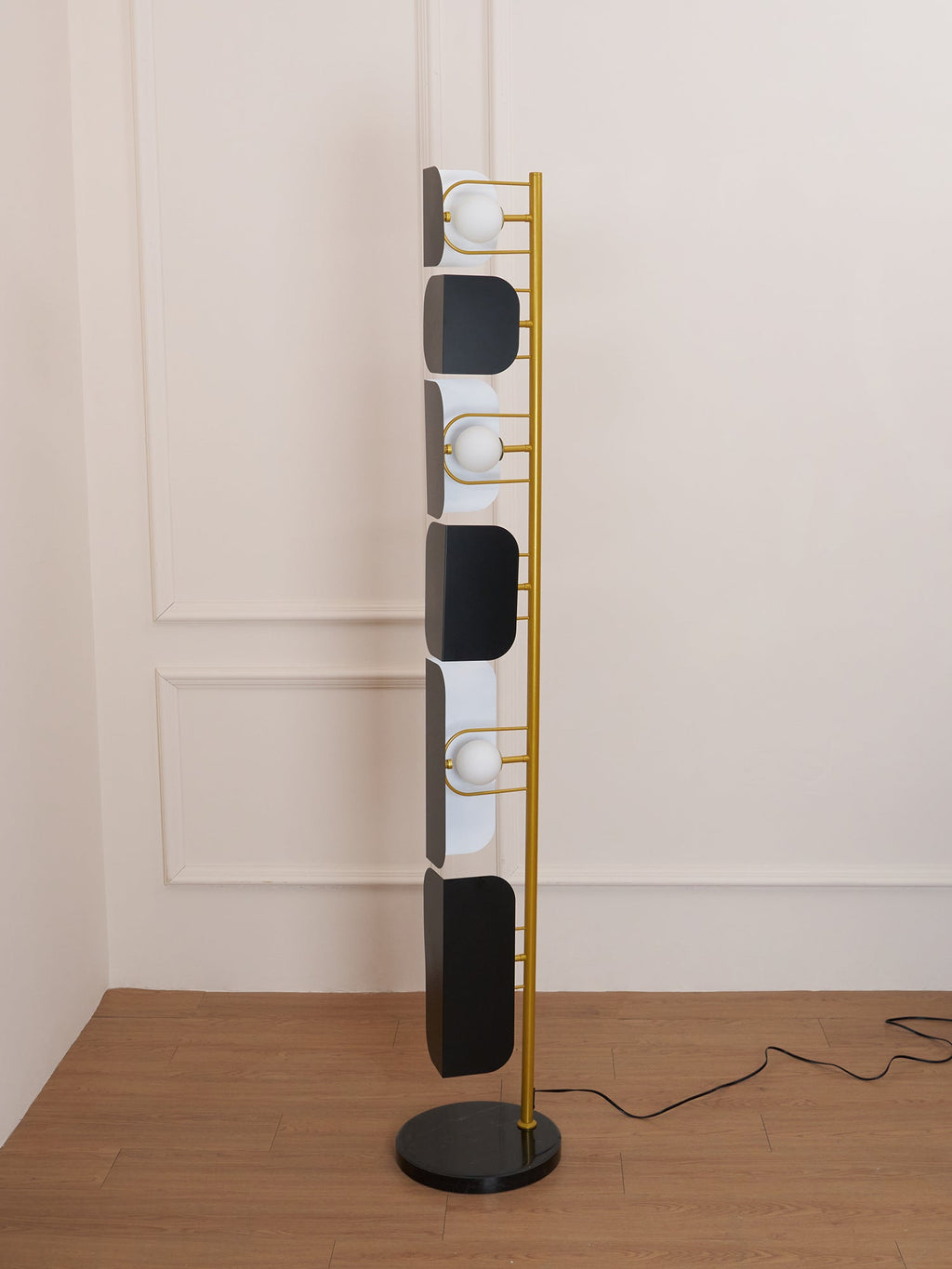 The Clérachic floor lamp's black glass panels and glowing opal globes alternate down its full length against a plain painted wall.