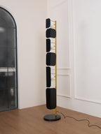 The Clérachic floor lamp stands near an arched frosted-glass door, its glass panels lit above the wood floor.