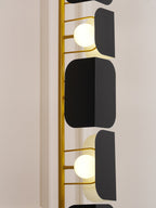 An extreme close-up of the Clérachic floor lamp's gold rungs, black glass panels and glowing globes against a plain unlit backdrop.