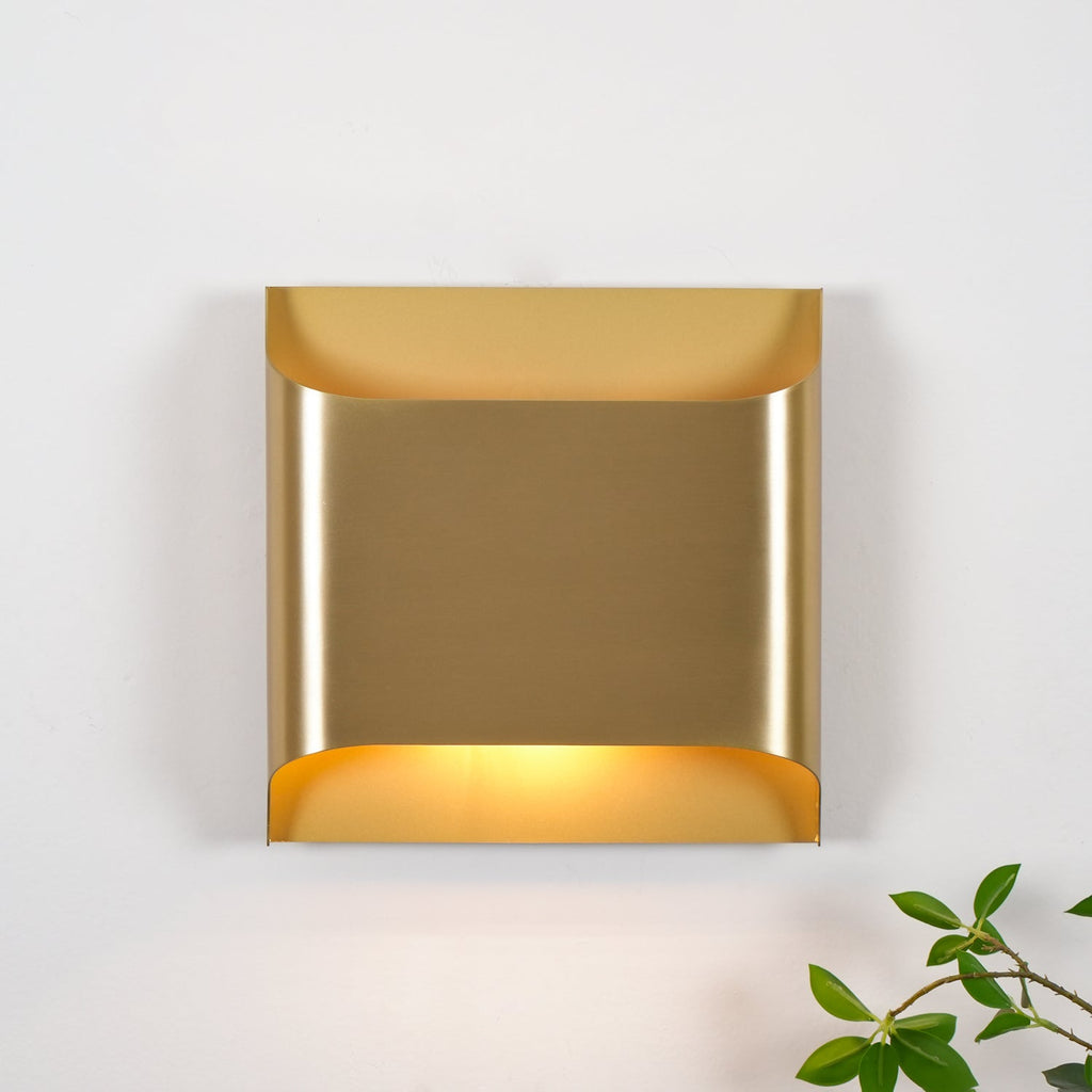 Solid brass slender wall sconce mounted beside a mirror