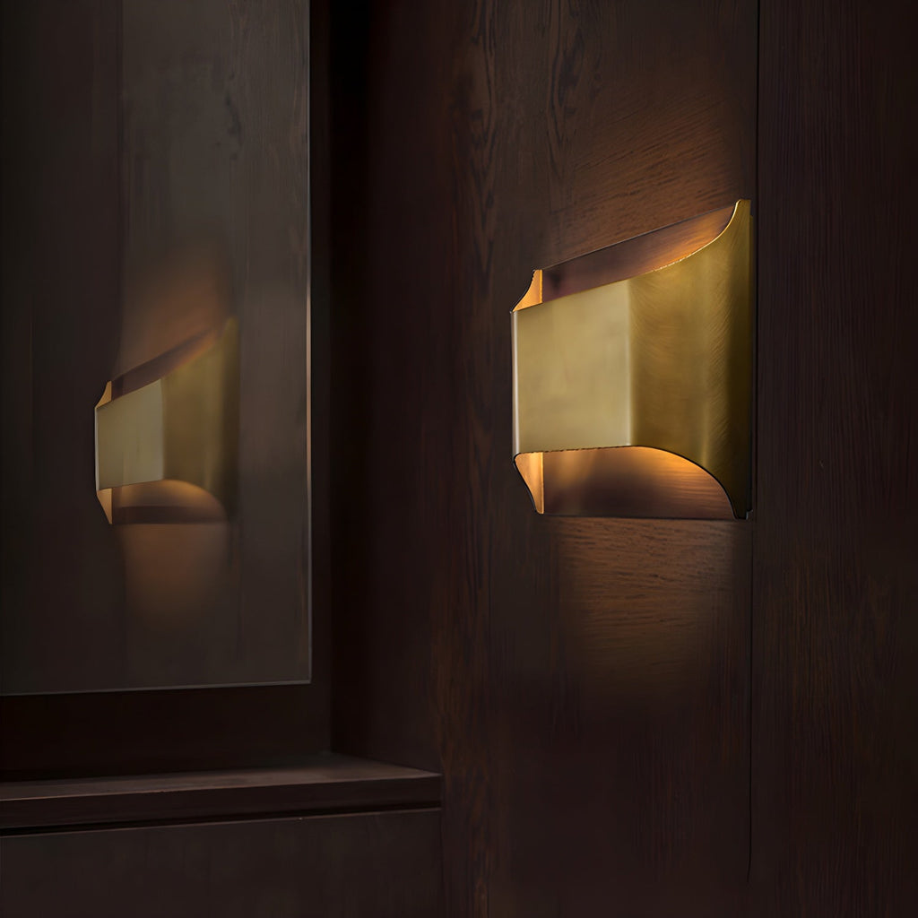 Brass wall sconce with Edison-style bulb on a bedside wall