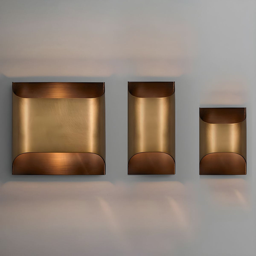 Solid brass wall sconce glowing warmly in a dim hallway