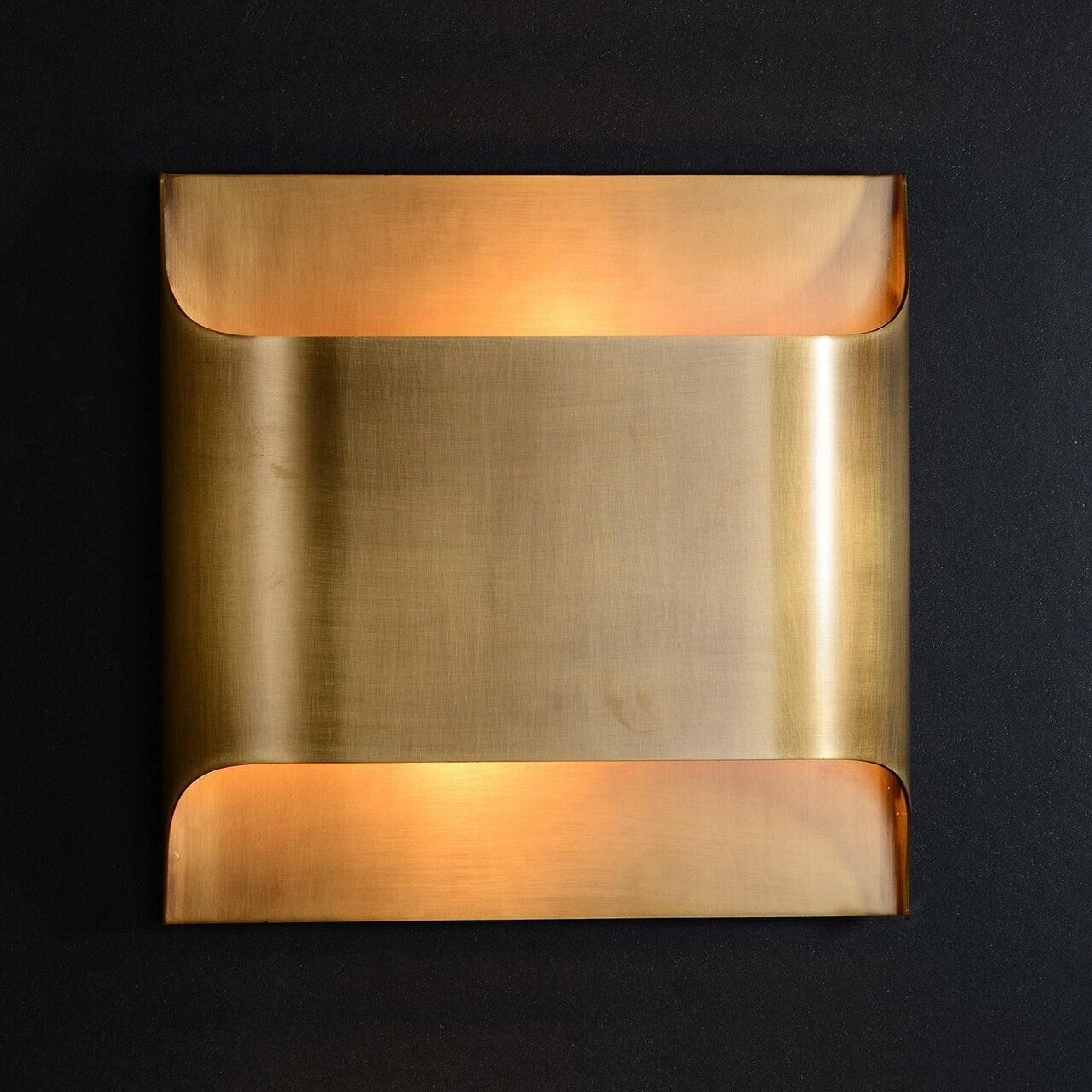 Matte black wall sconce with warm bulb on a plain wall