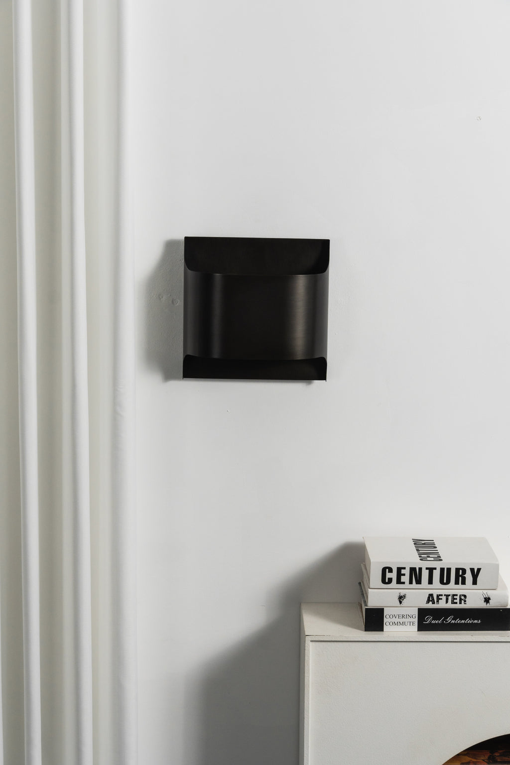 Matte black wall sconce with a rounded globe and warm glow